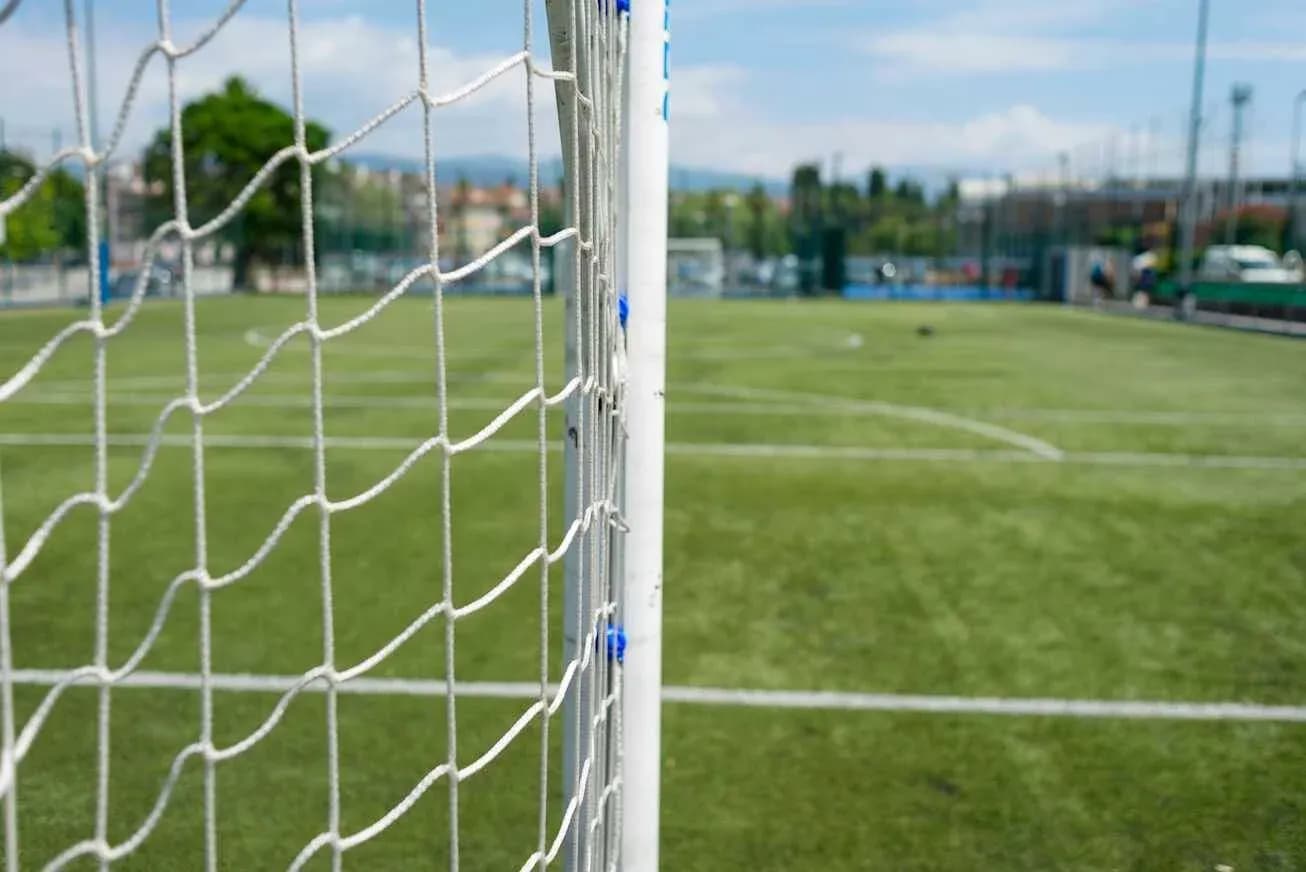 Red de gol en campo de fútbol en día soleado