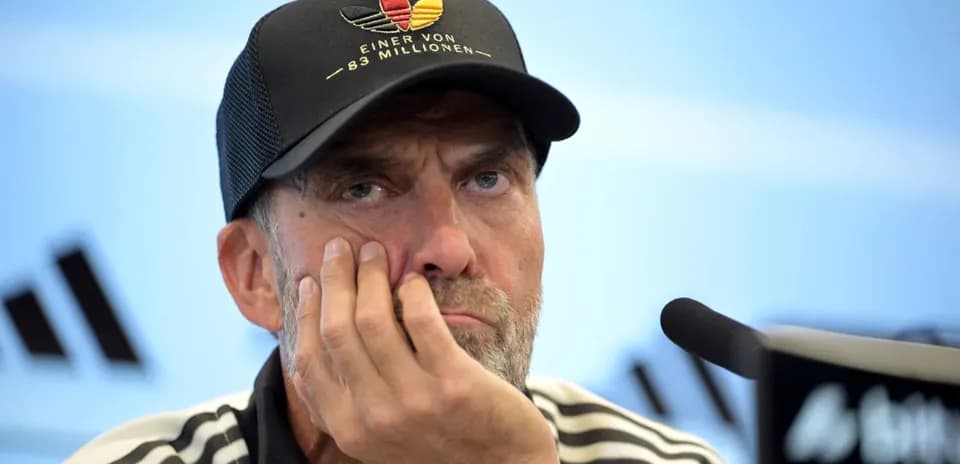 Entrenador en conferencia de prensa con expresión pensativa