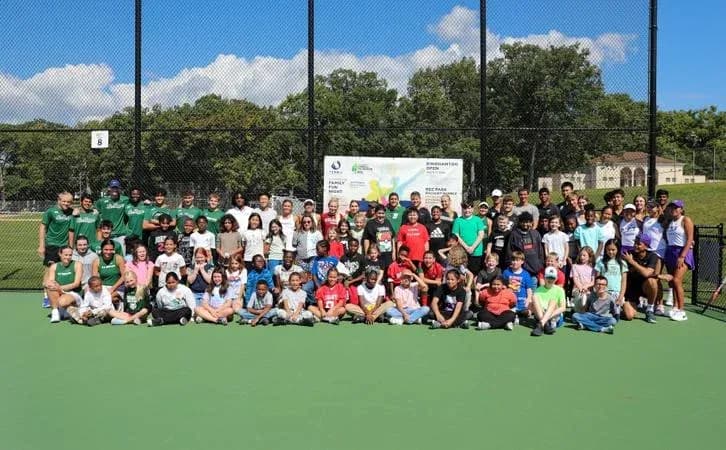 Grupo grande de personas en una cancha de tenis