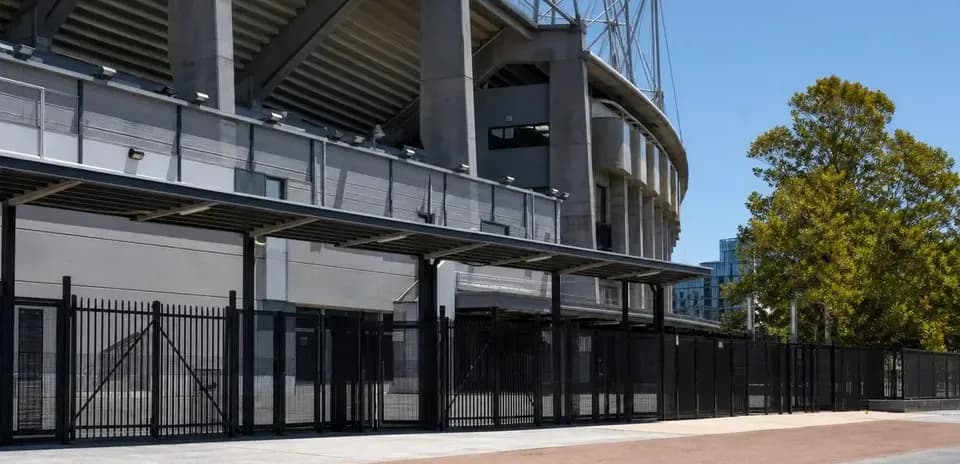 Fachada de estadio con cercas y árboles cercanos