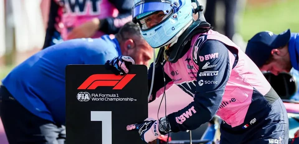 Piloto señalando el cartel de la Fórmula 1 en pits