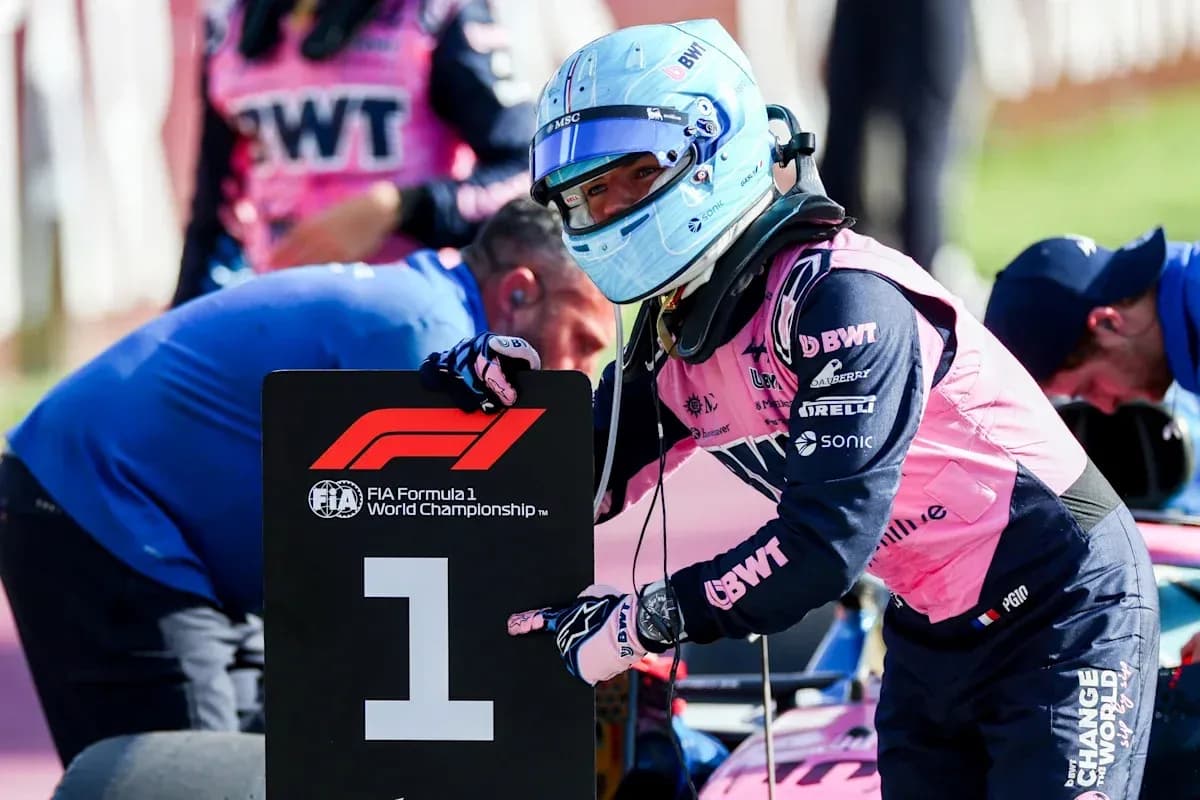 Piloto señalando el cartel de la Fórmula 1 en pits