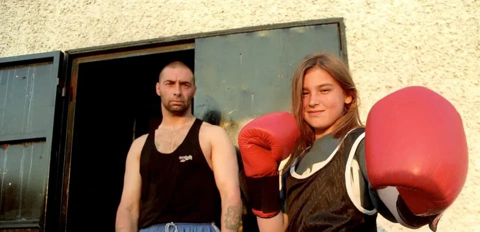 Boxeadora joven con guantes, hombre detrás en la puerta