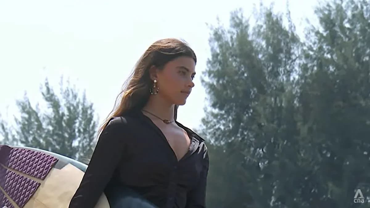 Mujer sosteniendo una tabla de surf en la playa Mujer sosteniendo una tabla de surf en la playa