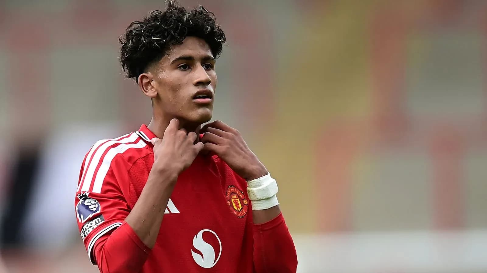 Jugador de Manchester United ajustándose el cuello del jersey Jugador de Manchester United ajustándose el cuello del jersey