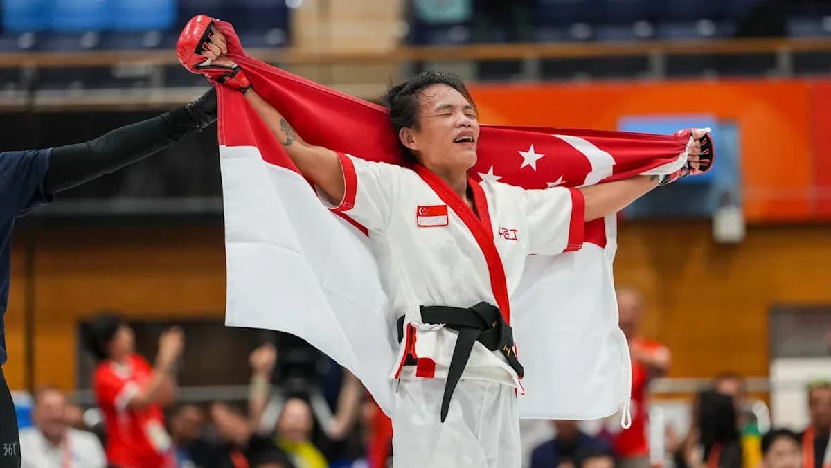 Atleta sosteniendo la bandera de Singapur tras la victoria Atleta sosteniendo la bandera de Singapur tras la victoria